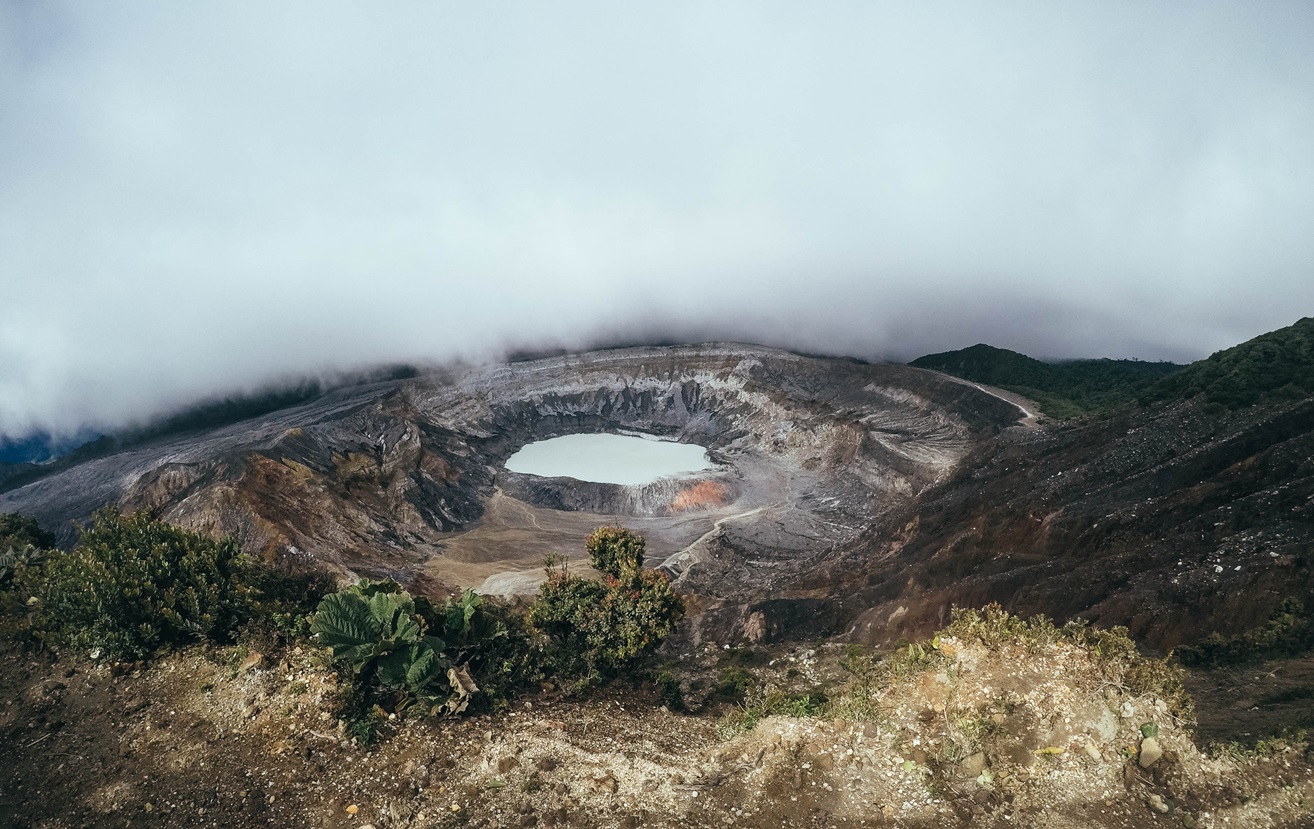 Crater surrounded by fog and black sand