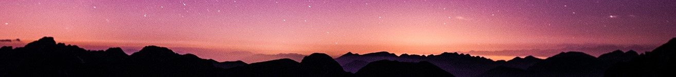 Dark mountains against a pink evening sky with stars