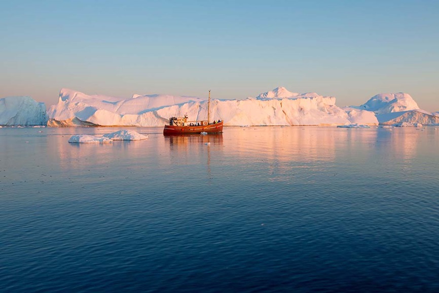 Research vessel in front of iceberg in Greenland