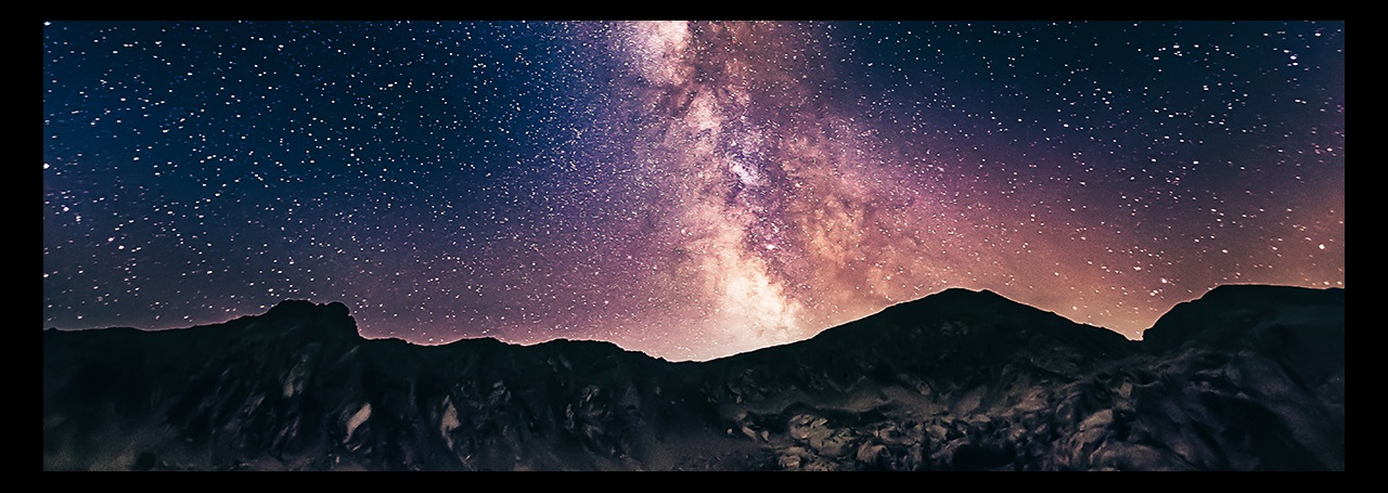 Mountains silhouetted against a starry night sky