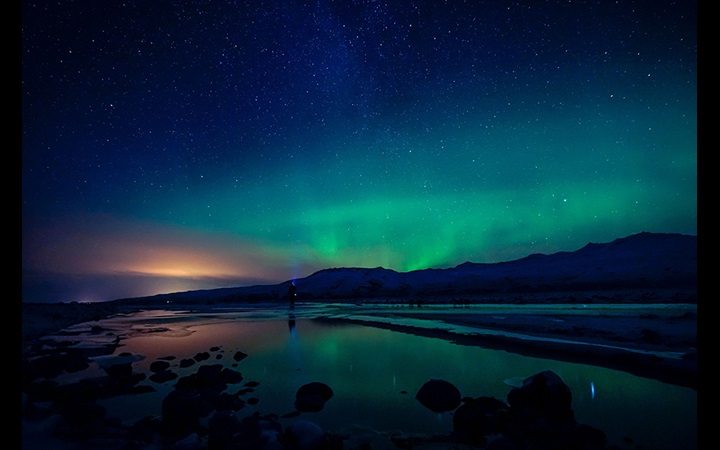Northern lights over coast with hills