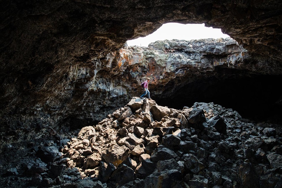 A hiker standing on a rock pile in the skylight of a tunnel