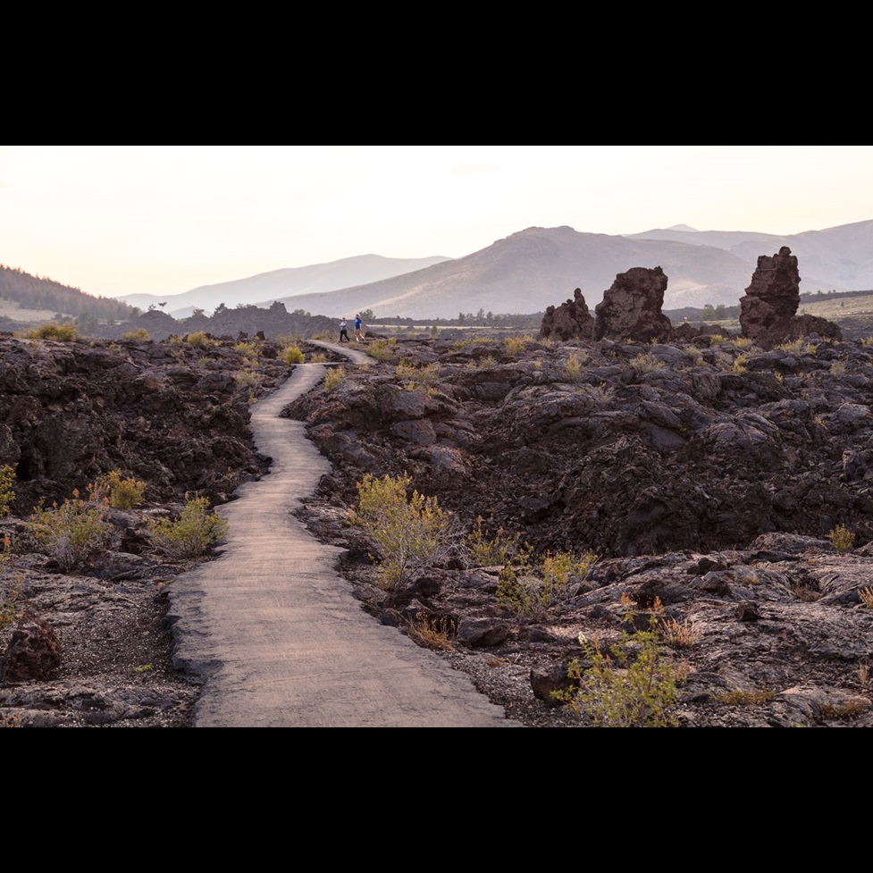 A hiking trail with two hikers in the distance at Craters of the Moon National Monument