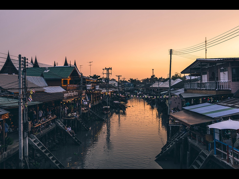A Thai floating marketing over calm water at sunset