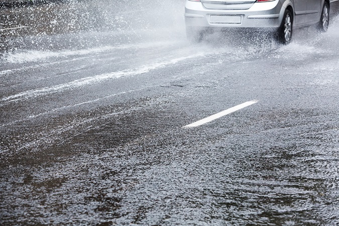 Car driving in the city street after heavy rain
