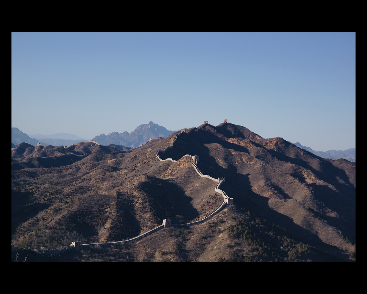 Brown mountains under a blue sky with the Great Wall of China