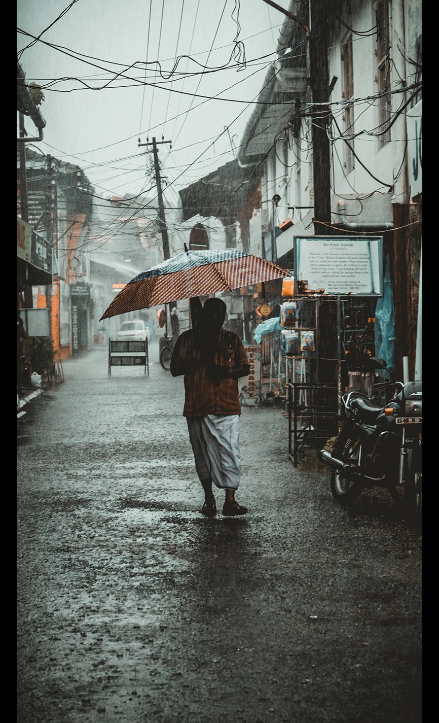 Man standing in a street under an umbrella in a rain storm 