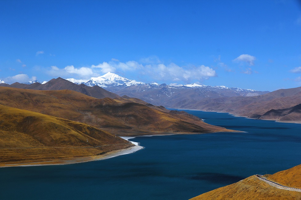 A blue river surrounded by Tibetan mountains