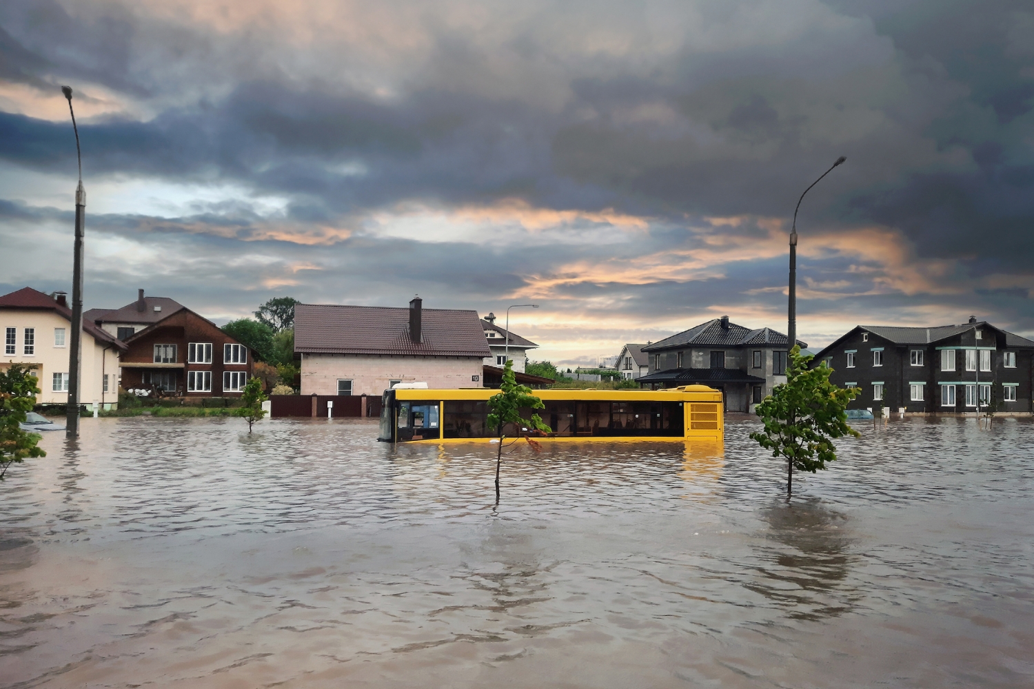 A yellow schoolbus in high waters on a flooded neighborhood street
