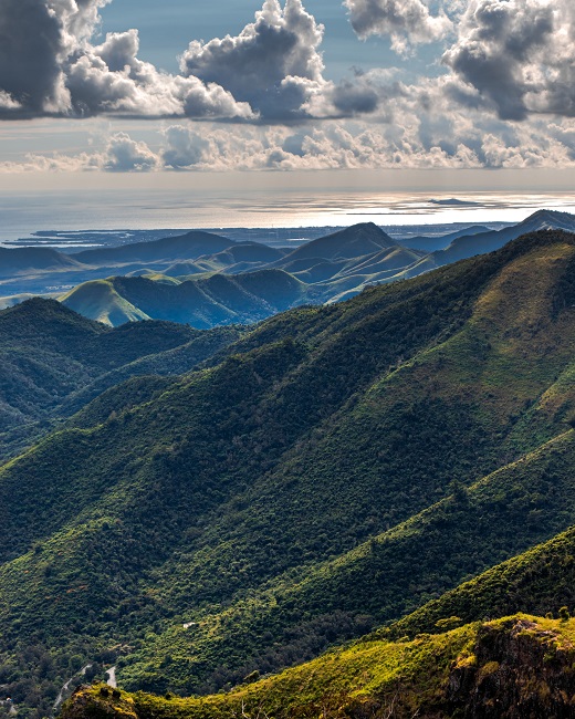 A distant view of the ocean from green tree covered mountains in Puerto Rico