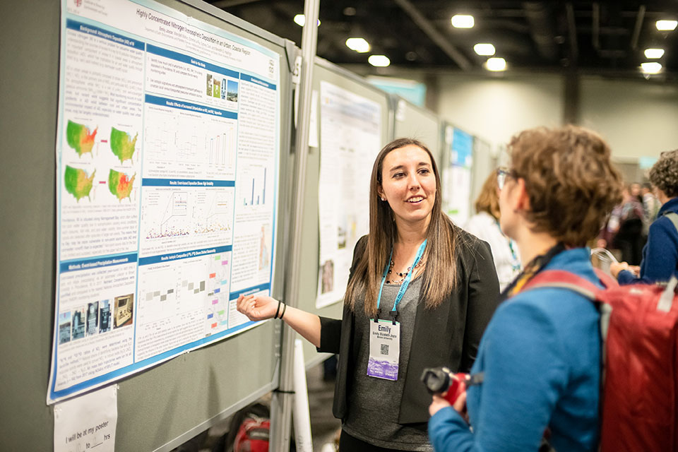 Woman explains poster to another woman attendee