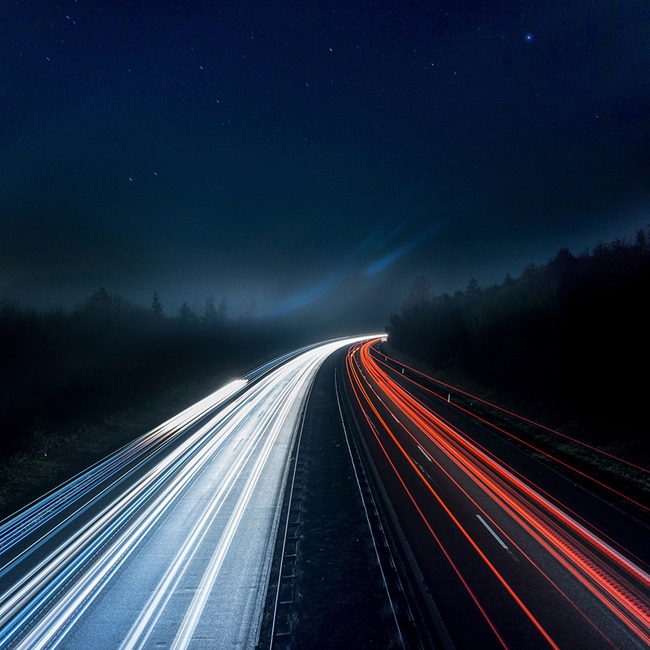 Roadway at night with light beams from cars