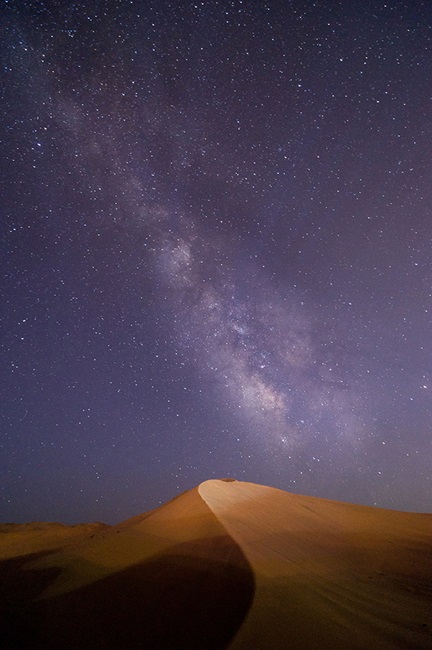 Desert dune with starry night sky in background