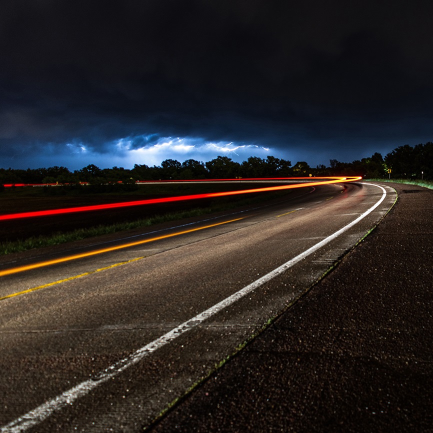 Roadway at night with lightbeam from cars