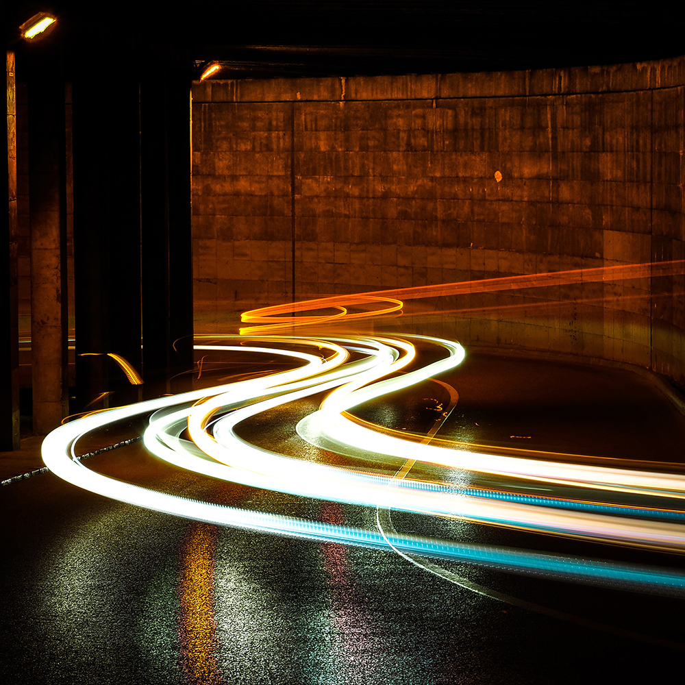 Light beams from cars driving through a stone tunnel