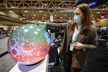 Woman touches globe at AGU Fall Meeting