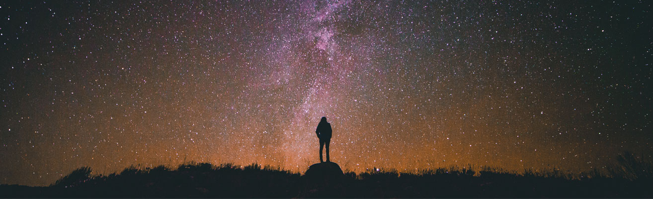 silhouette of a person gazing up at stars and milky way