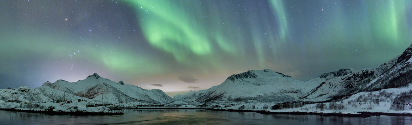 Northern Lights with snow covered mountains and a lake in the foreground