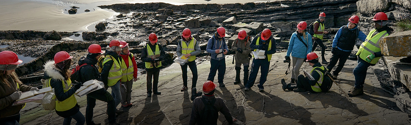 A group of scientists gathered on flat outcropping of rock overlooking a shoreline.
