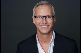 Headshot photo of man smiling with glasses
