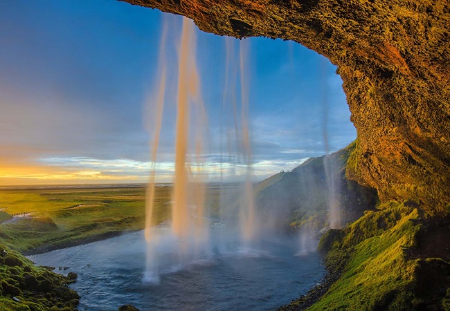 View of waterfall from inside a cave with sunlight