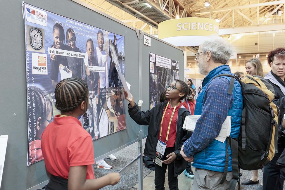 Young boy explaining poster to adult