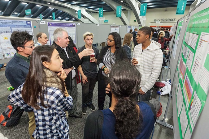 A group of students and teacher having a discussion in the poster hall