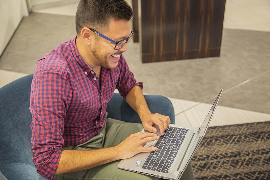 man smiling and typing on computer