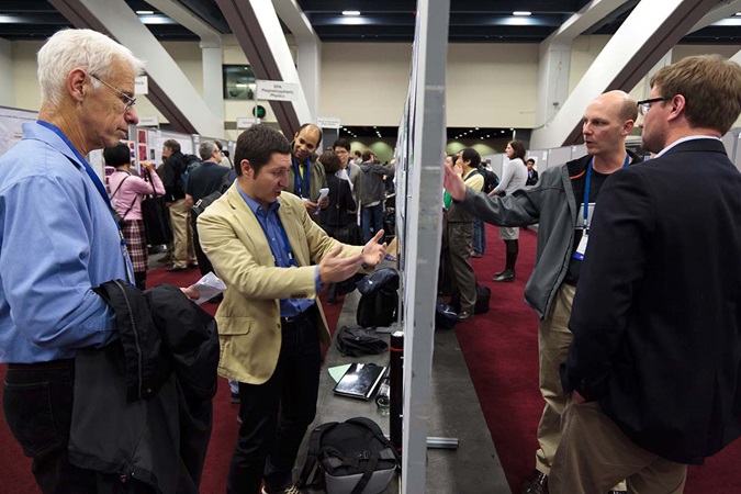 two groups of men explaining posters on both sides of the poster wall Fall Meeting poster hall
