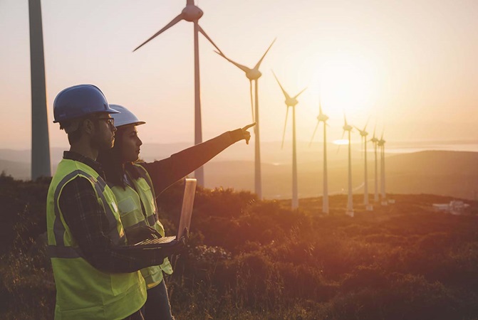 Young engineers standing in front of wind turbines