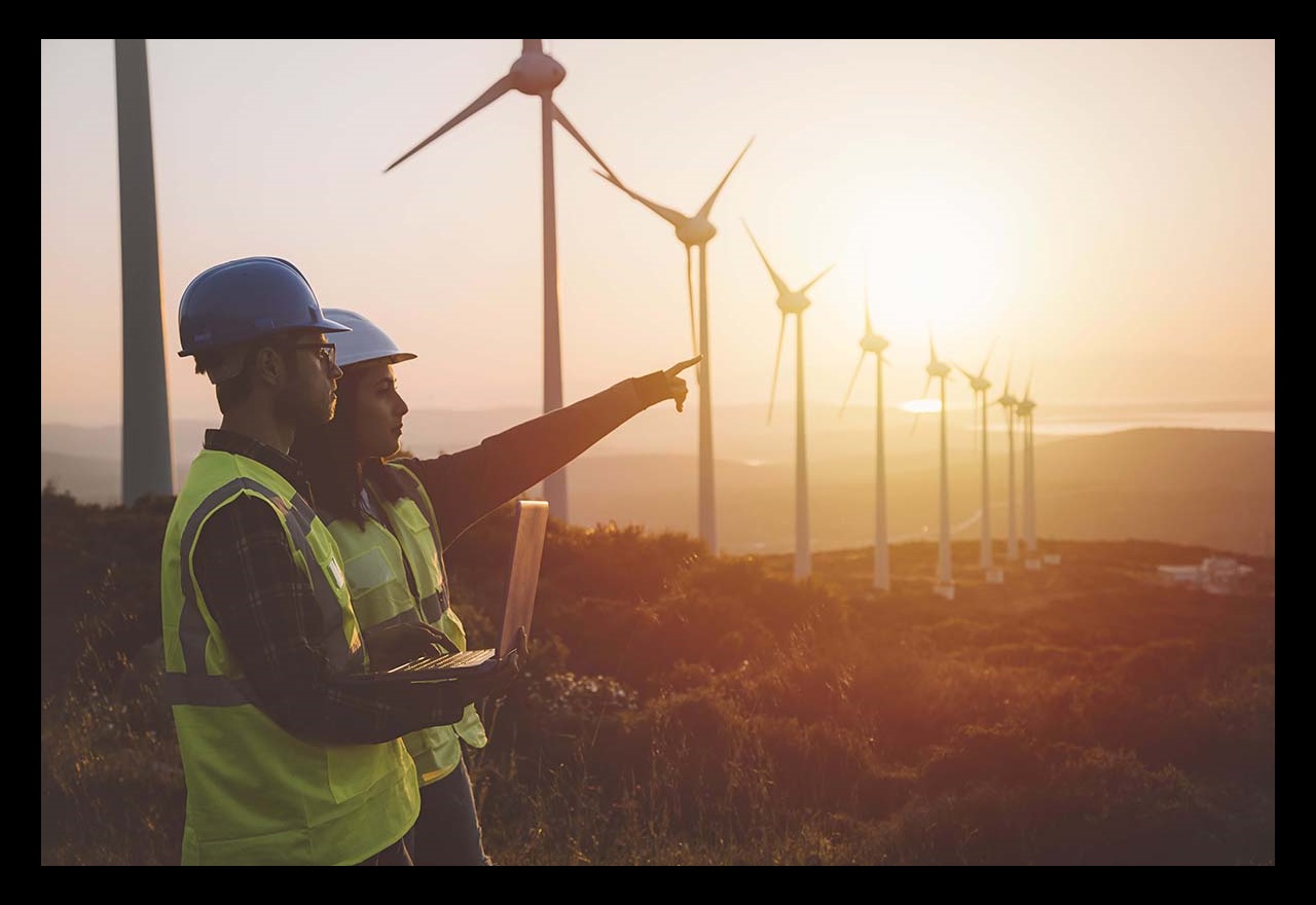 Young engineers standing in front of wind turbines