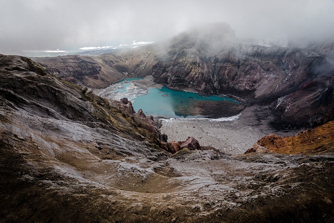 Lake at bottom of crater on a foggy day