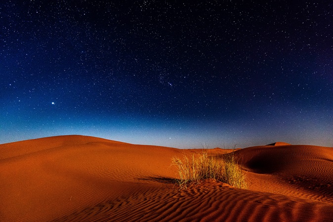 Nighttime stars over sandy desert dunes