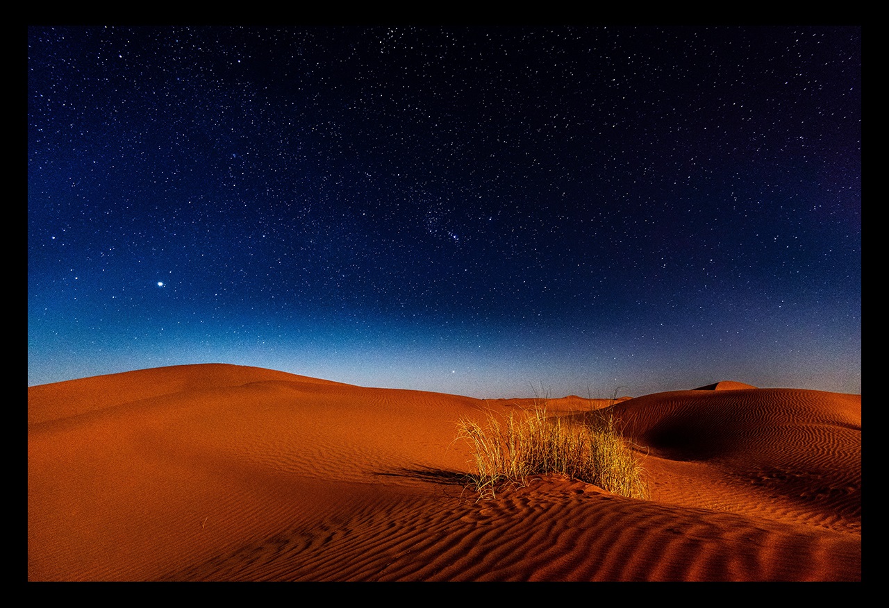 Nighttime stars over sandy desert dunes