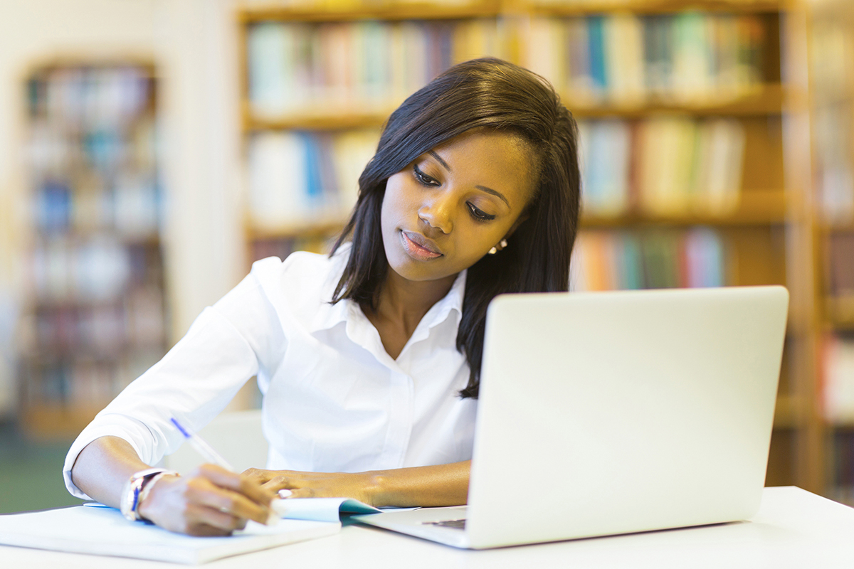female student writing in library