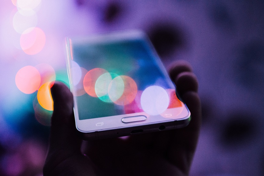 Person holding phone with colorful lights in background