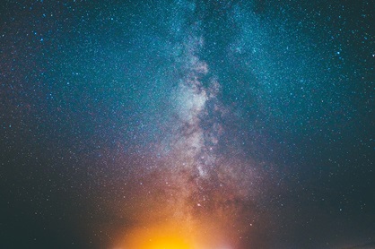 dark blue sky with stars, the Milky Way and a sunburst at the bottom