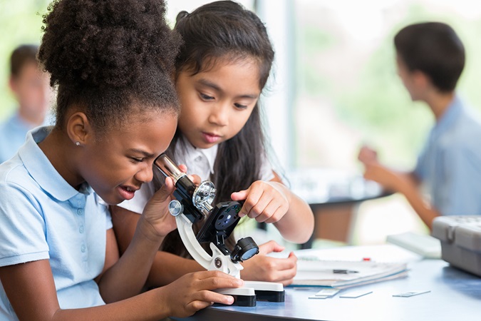 Young female students looking at something with a microscope