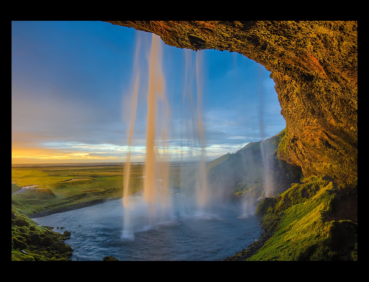 View of waterfall from inside a cave with sunlight
