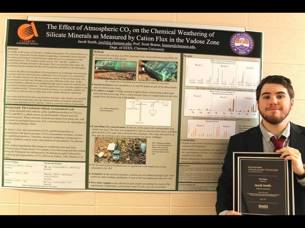 VPS winner Jacob Smith stands in front of his poster presentation holding his winner's plaque.