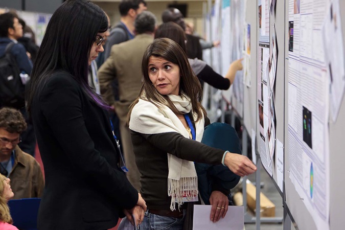 woman explaining poster to woman in poster hall