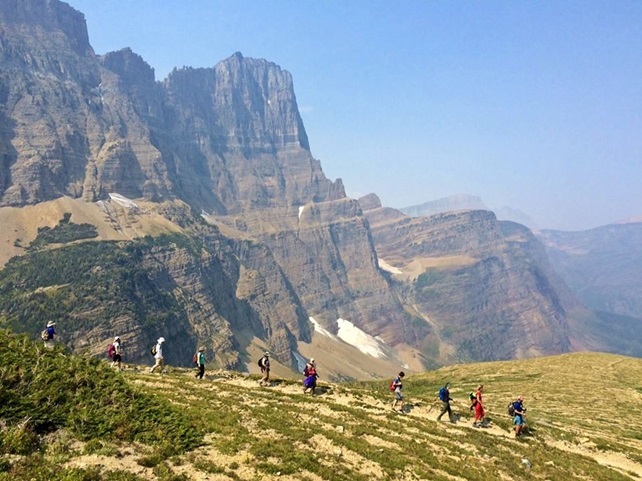 People hiking on trail along mountains and cliffs