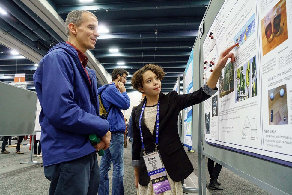 Student showing teacher their poster group of people