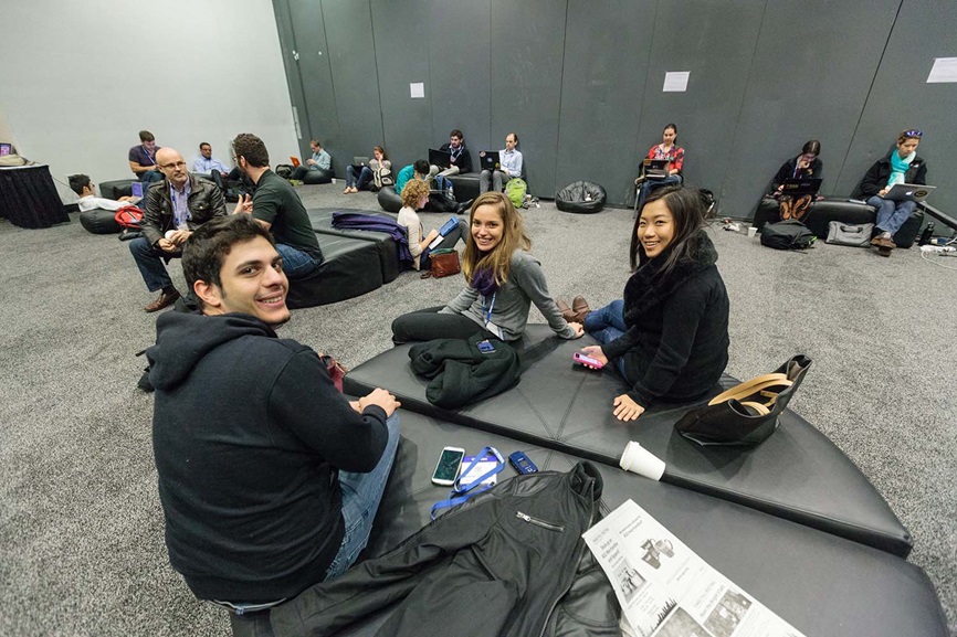 Students sitting on cushioned seats in a big open lounge Info for mentees