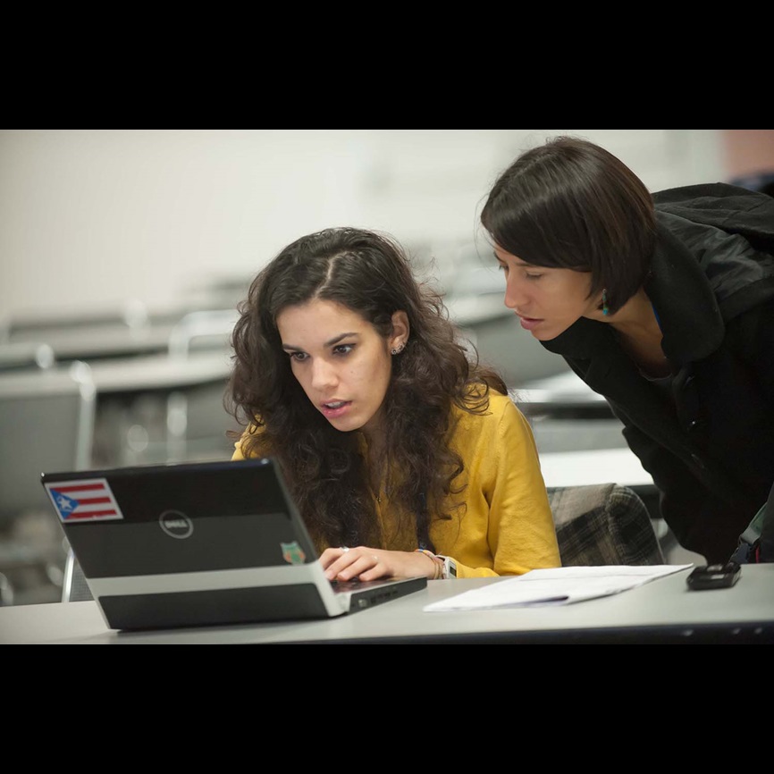 Teacher helping student on computer woman writing
