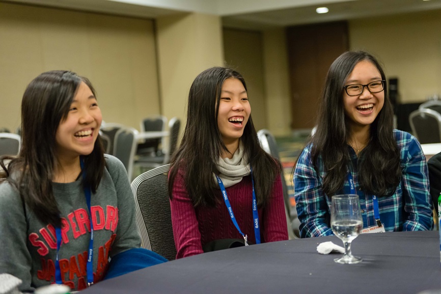 Three female students sit at a table laughing