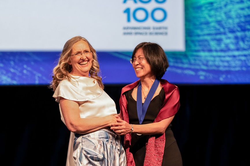 AGU President Robin Bell shakes hands and laughs with a new AGU Fellow