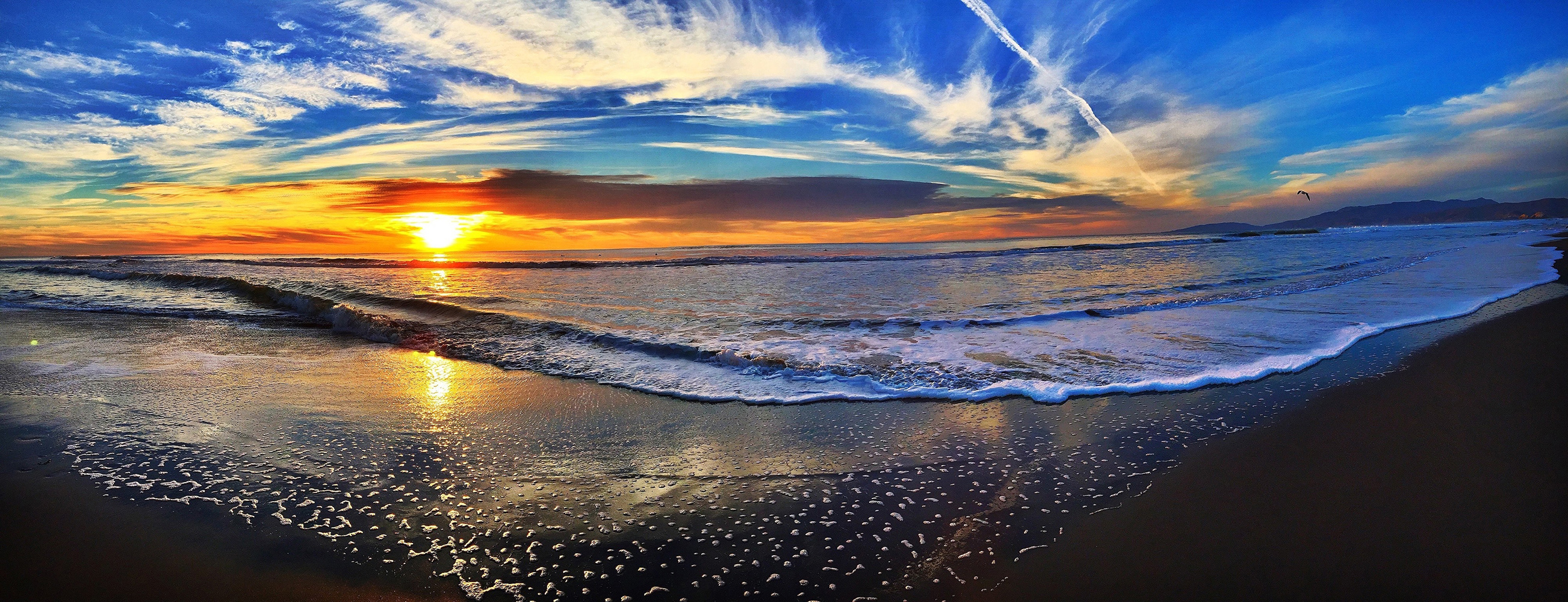 Beach view at dawn with bright sun and blue skies