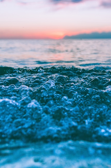 Ocean waves with foam and sunset background