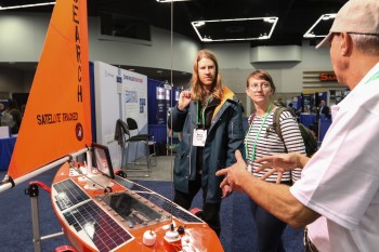 Three people look at 2-meter drone sailboat with solar panels 